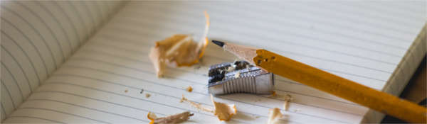 Image of sharpened pencil ready to write on blank notebook
