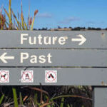 Painted wooden sign pointing to past and future