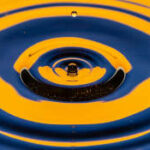 Ripples on water caused by a falling drop, in a warm orange-yellow with blue contrast