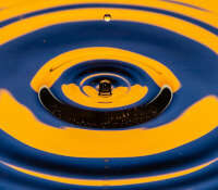 Ripples on water caused by a falling drop, in a warm orange-yellow with blue contrast