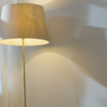 Two people in conversation, looking tense, with a standard lamp between them in the background