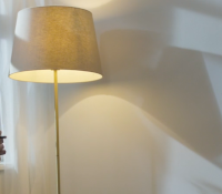 Two people in conversation, looking tense, with a standard lamp between them in the background